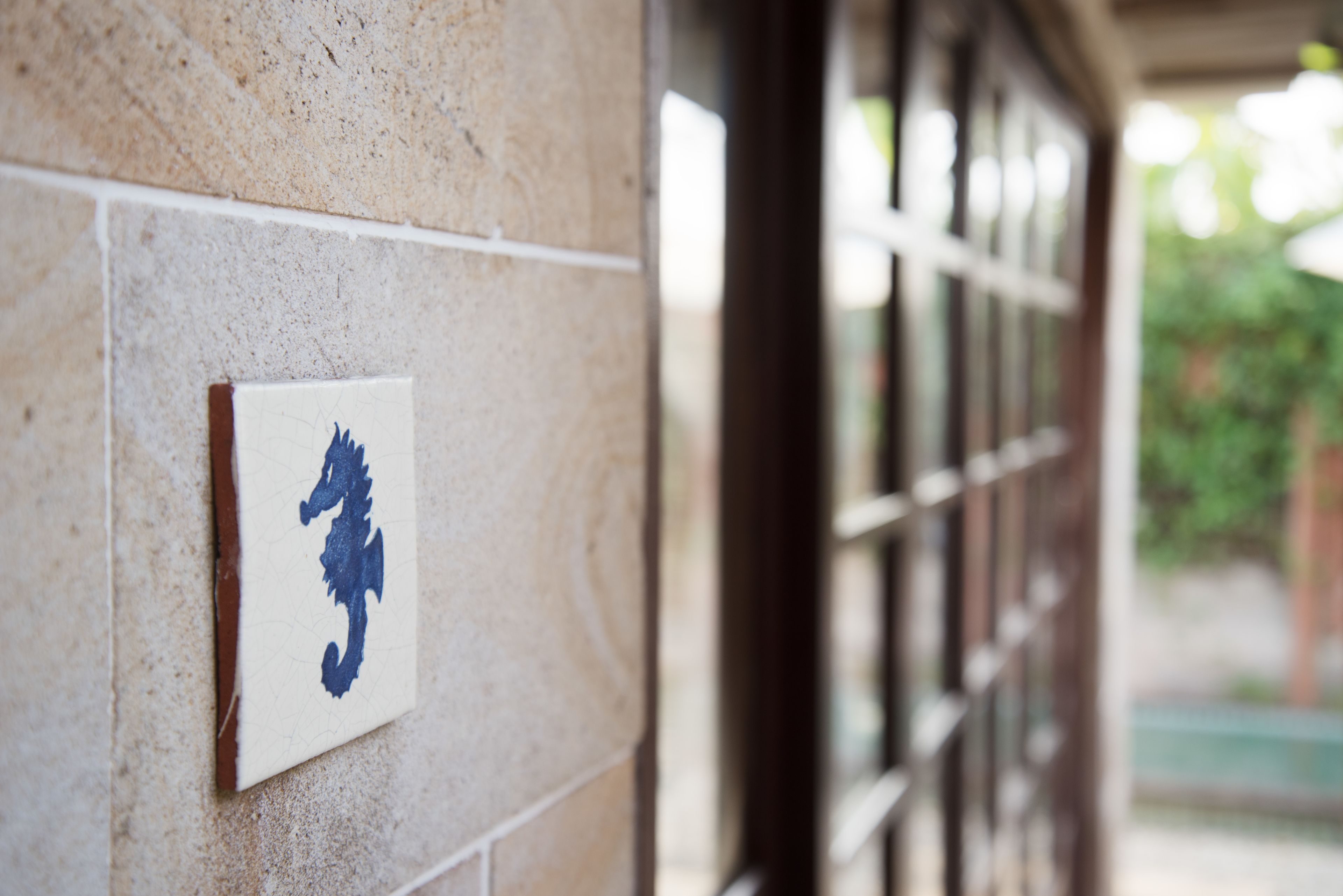 Un mur recouvert de carreaux, orné d’un symbole représentant un hippocampe bleu.