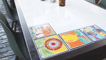 A dining table with a colorful tablecloth, a vase with a plant, and a decorative lamp.