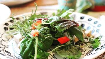 A plate of mixed greens salad with red bell peppers and cheese on a decorative plate.