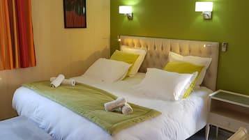 A neatly made bed with white and green bedding, two bedside lamps, and a nightstand with a drawer.