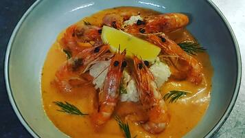 Un plato de camarones en salsa cremosa con limón y hierbas.