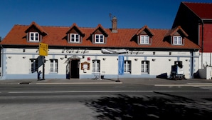 A traditional building with a red-tiled roof, multiple windows, and a sign indicating it is a restaurant.