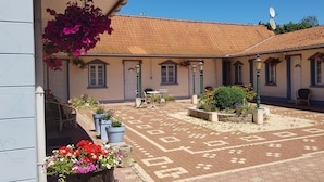 A courtyard with a patterned floor, outdoor seating, and potted plants.