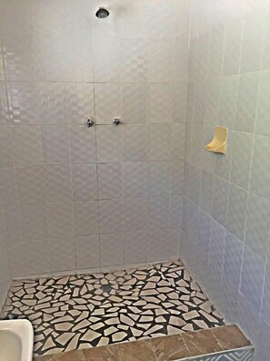 Een douche met betegelde vloer en een wandhouder voor handdoeken.
