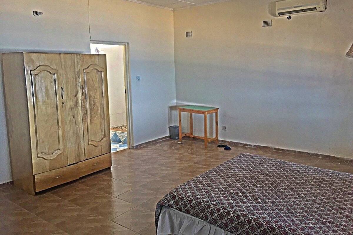 Een kamer met een bed, een kledingkast en een klein tafeltje.