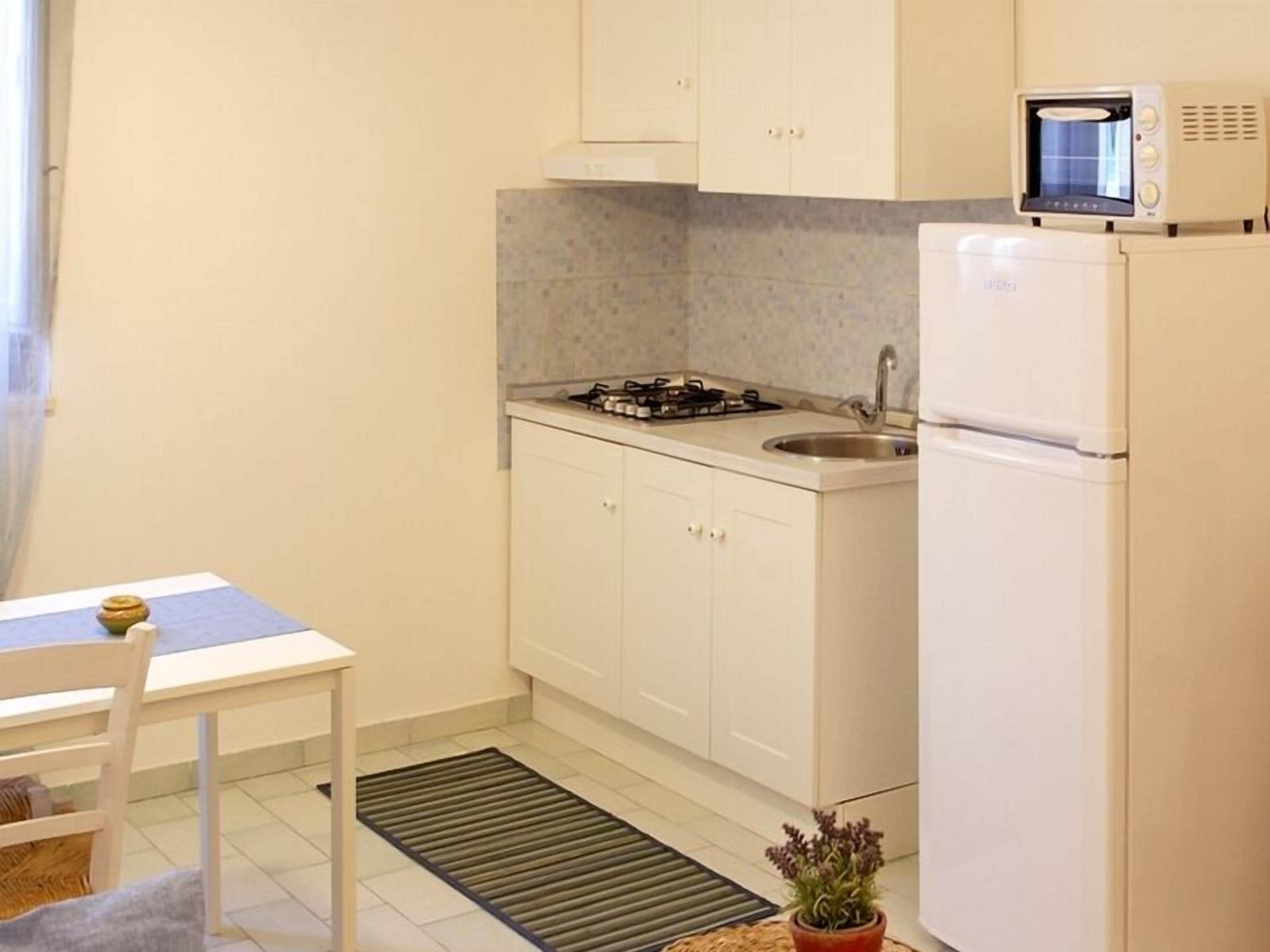 A small kitchenette with a microwave, stove, sink, and refrigerator.