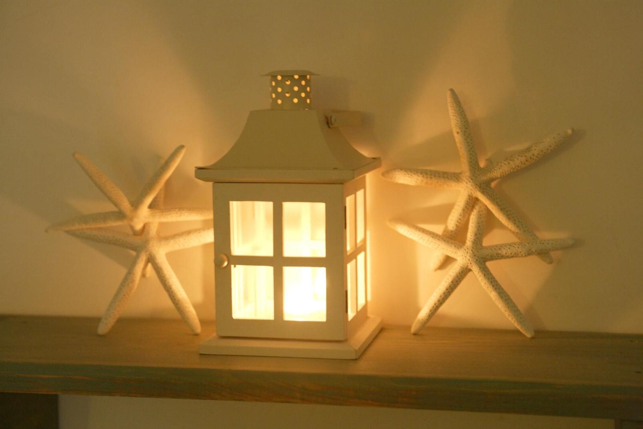A white lantern with a hexagonal window design, placed on a wooden surface.