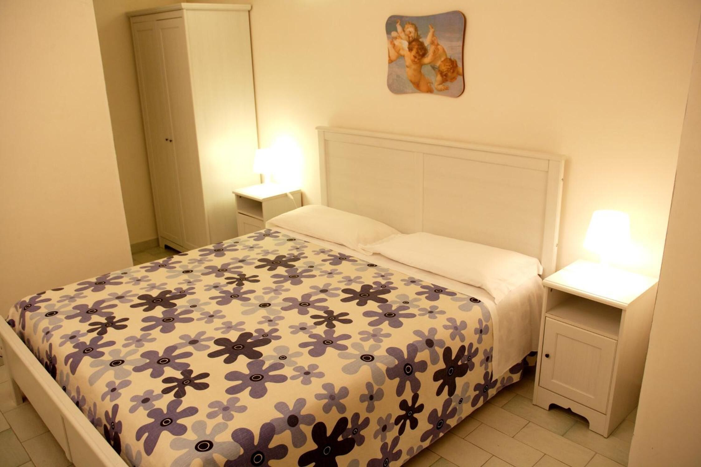 Un dormitorio con cama, mesitas de noche, armario y un adorno en la pared.
