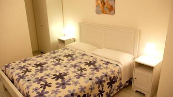 Un dormitorio con cama, mesitas de noche, armario y un adorno en la pared.
