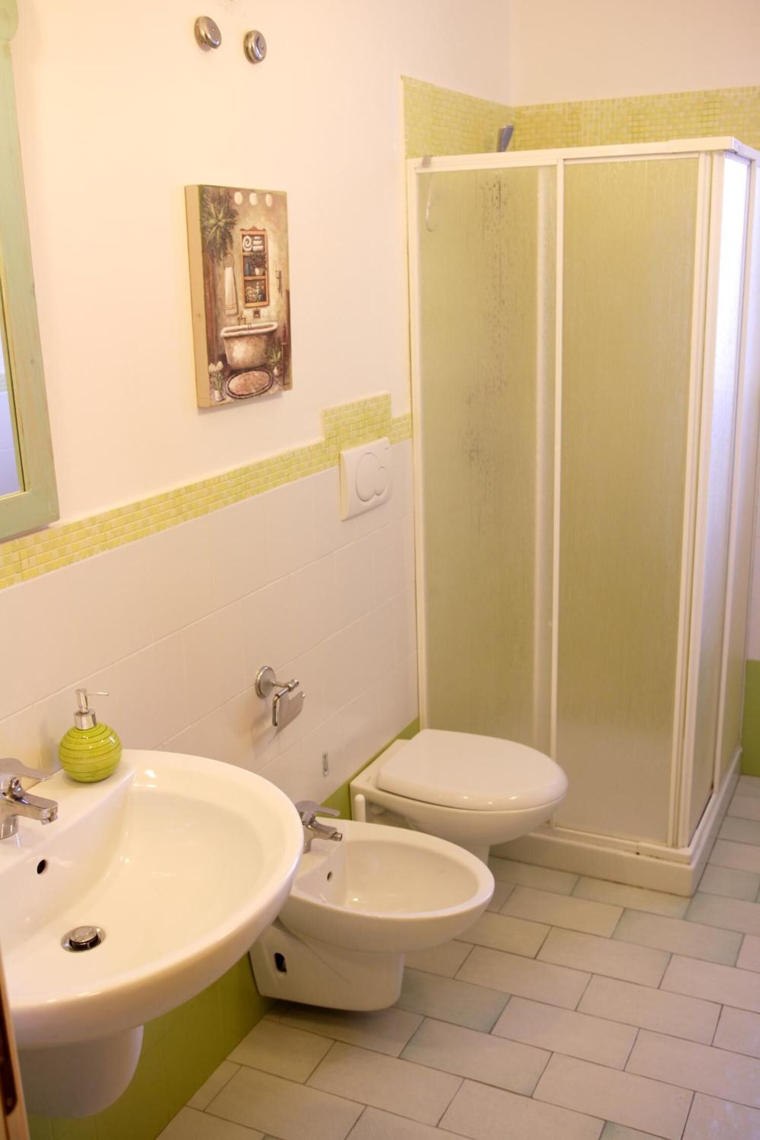 A bathroom with a sink, two toilets, and a glass-enclosed shower.