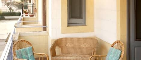 A balcony with wicker furniture, a small table, and two lanterns.