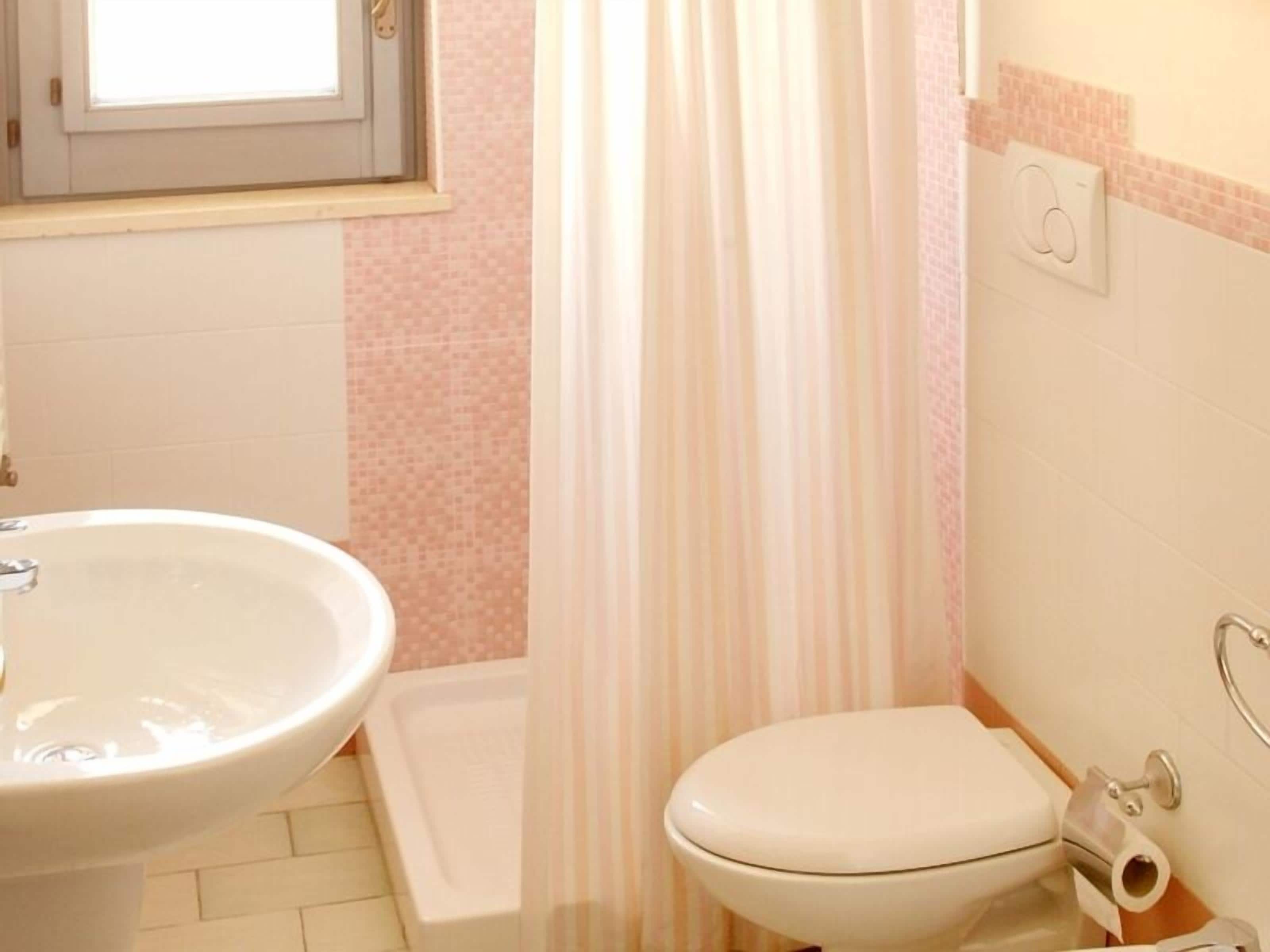 A bathroom with a white sink, toilet, and shower curtain.