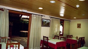 Un espace repas avec des tables et des chaises en bois, un mur en pierre et une vue sur l’extérieur.