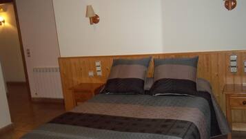 Une chambre à coucher avec une tête de lit en bois, un lit avec plusieurs oreillers, une table de chevet et une lampe fixée au mur.