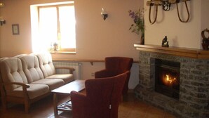 Un salon chaleureux avec une cheminée, un canapé et deux fauteuils.