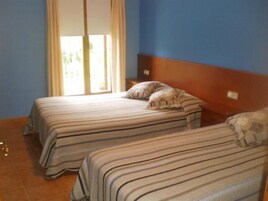 Una habitación con dos camas, una ventana con cortinas y un cabecero de madera.