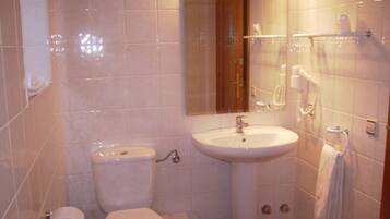 Een badkamer met toilet, wastafel en spiegel.
