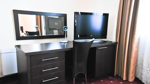 Une chambre d’hôtel équipée d’un bureau, d’une chaise, d’une télévision et d’un miroir.