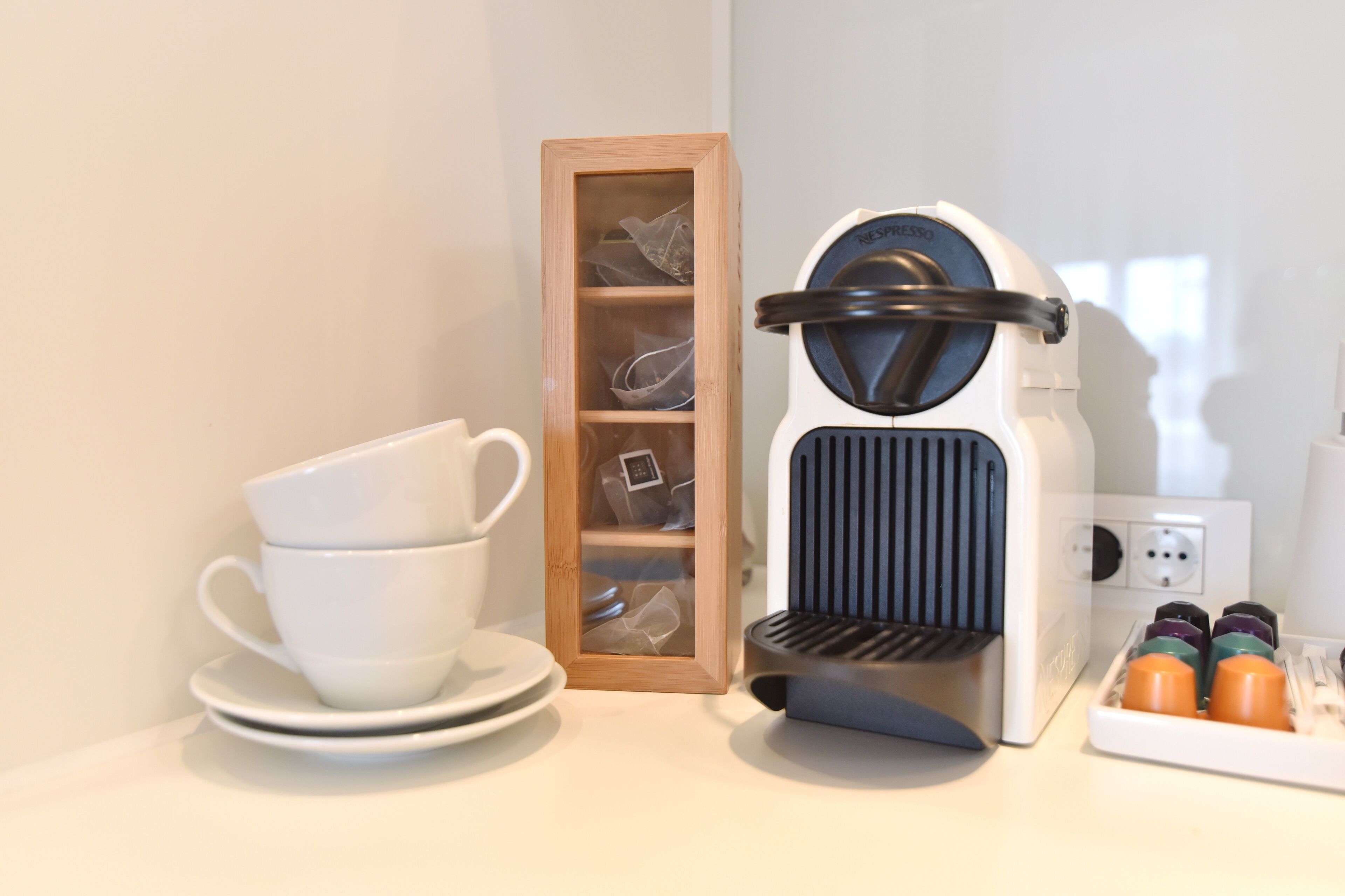 En kaffebryggare, en kopp och ett fat, samt en förvaringslåda med diverse föremål i.