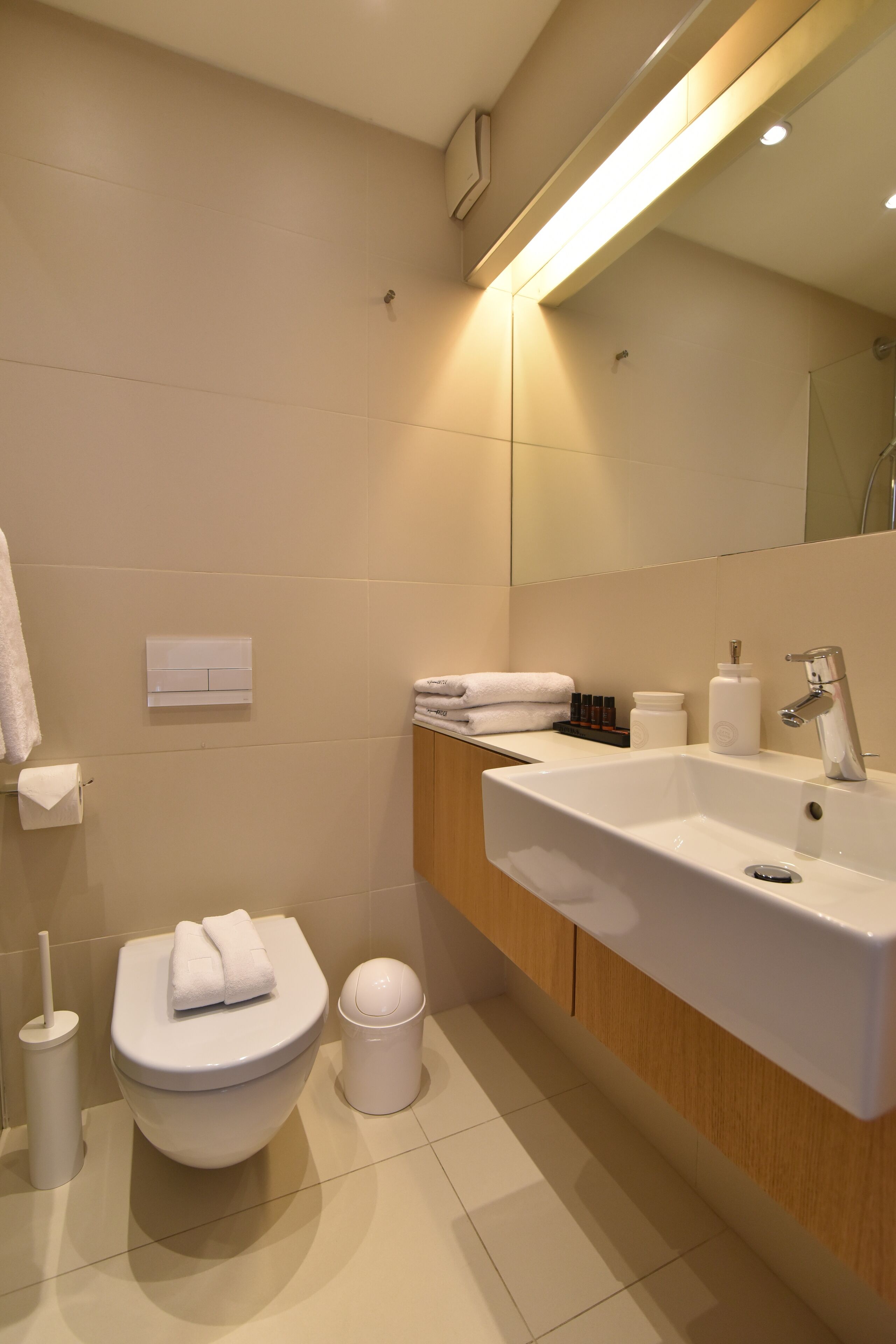 A modern bathroom with a toilet, sink, and mirror.