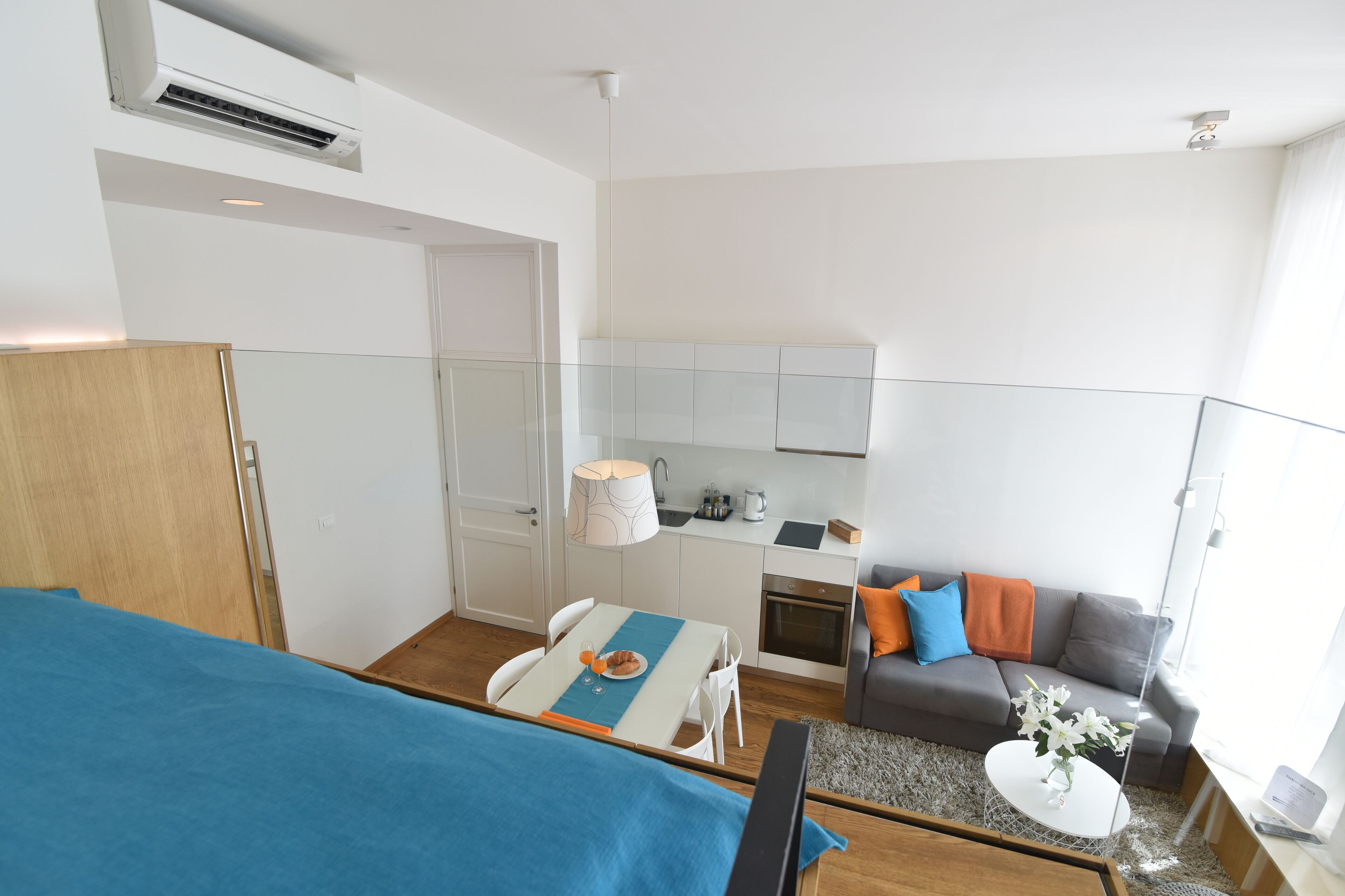 Un espace de vie compact comprenant un coin cuisine, un coin repas et un espace détente avec un canapé et une table basse.