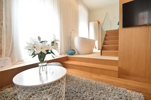 Ein modernes Badezimmer mit Badewanne, Holztreppe und einem an der Wand befestigten Flachbildfernseher.