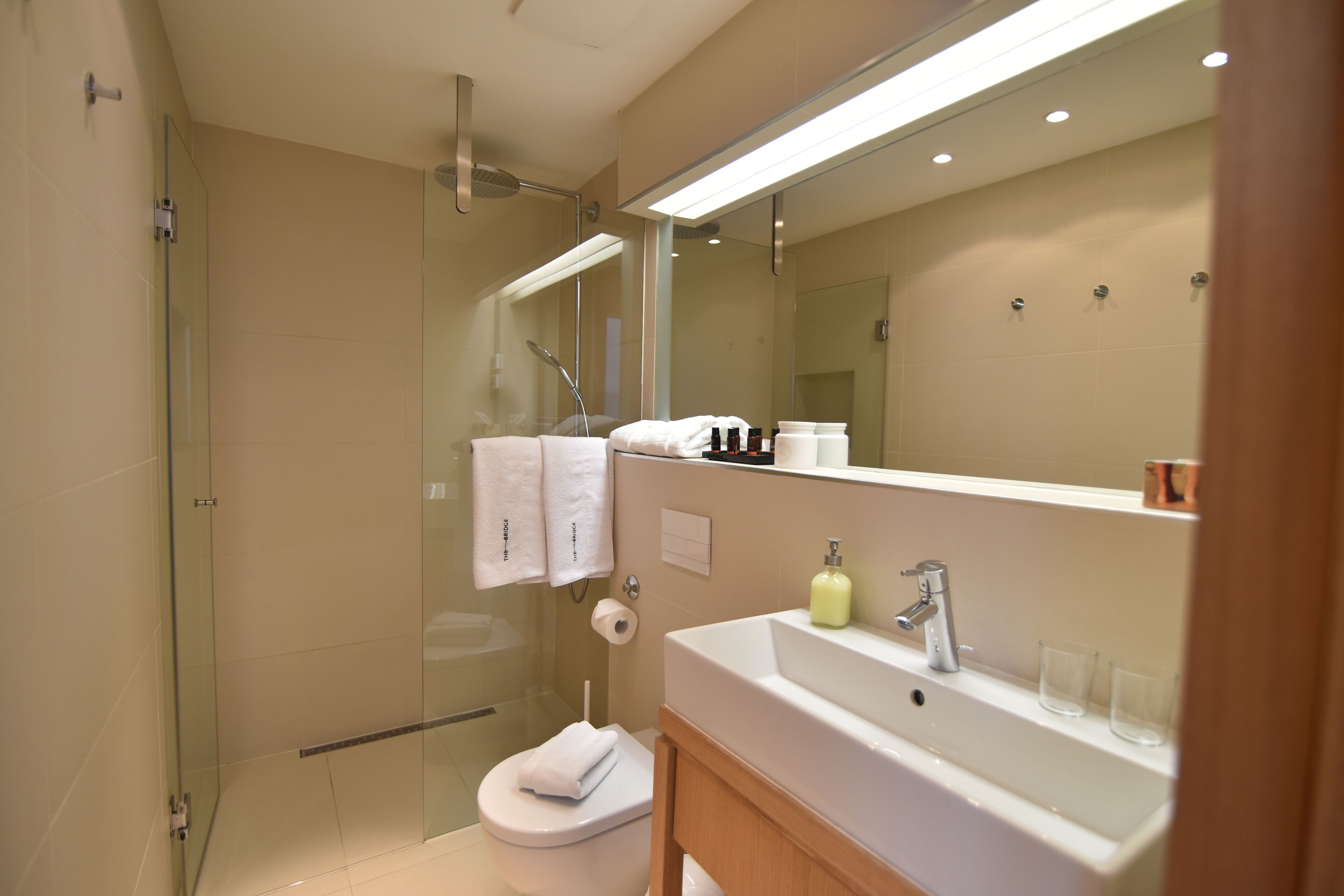 A modern bathroom with a glass-enclosed shower, a white sink, and a large mirror.