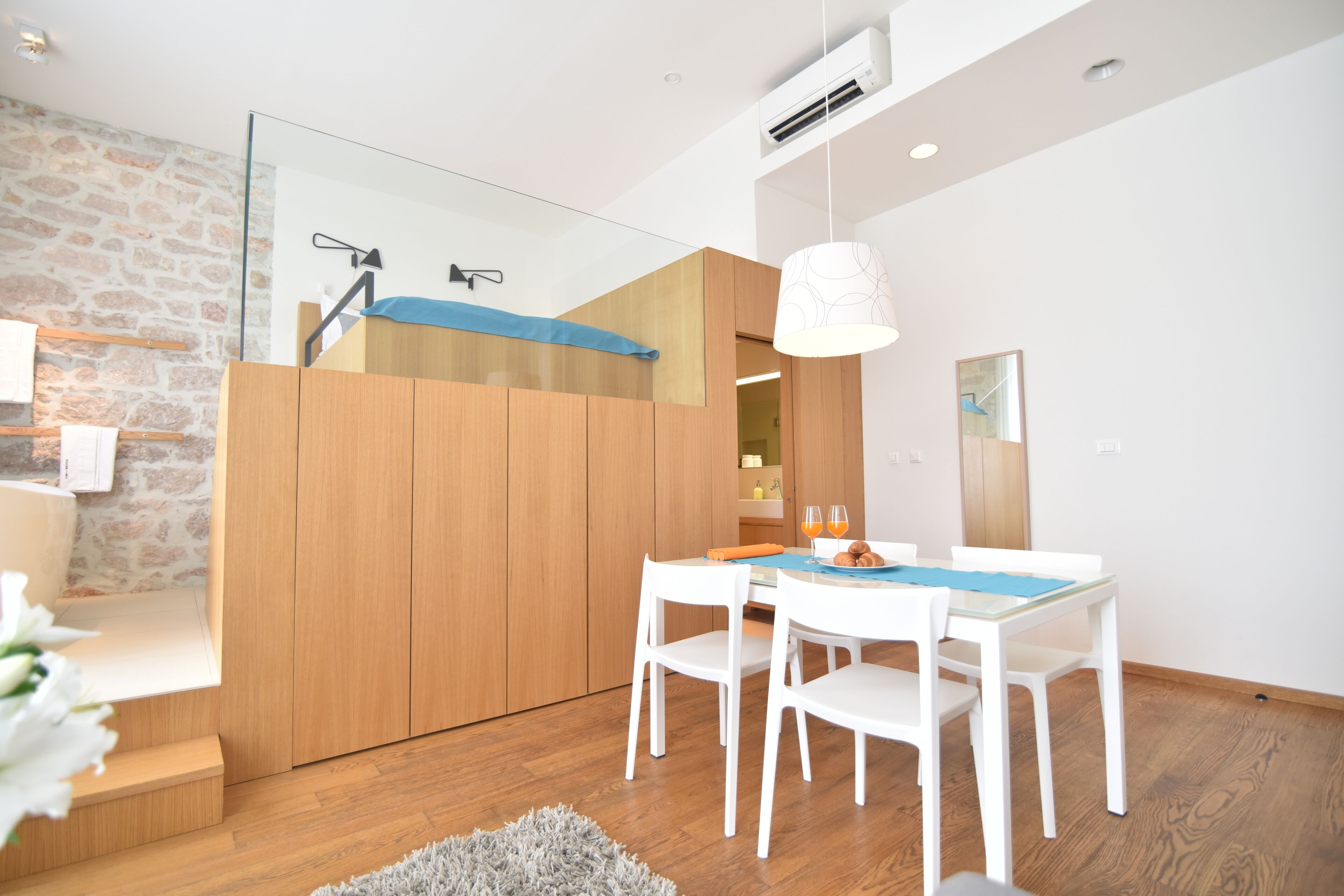 A modern kitchen with wooden cabinets, a dining table with white chairs, and a built-in oven.