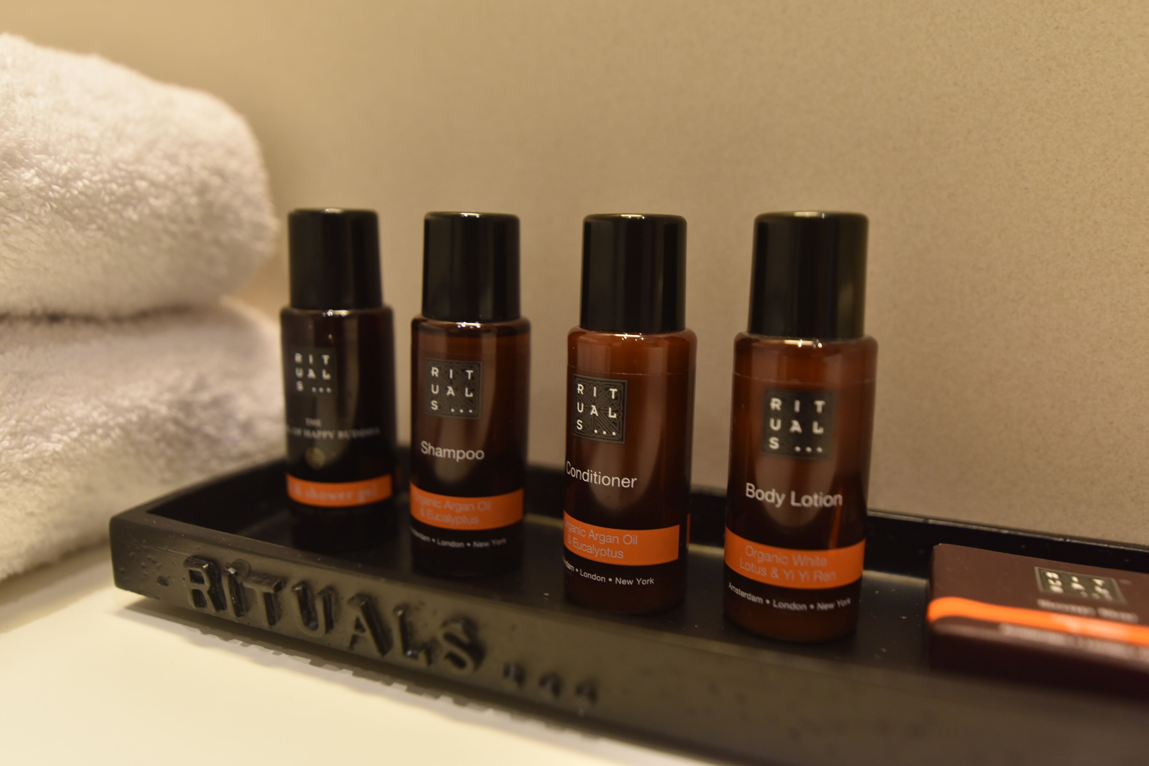 A tray with bottles of Rituals body care products including shampoo, conditioner, and body lotion.