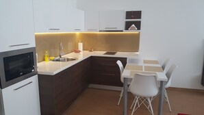 Une cuisine compacte équipée d’un four à micro-ondes encastré, d’un évier et d’un petit coin repas avec une table et des chaises.