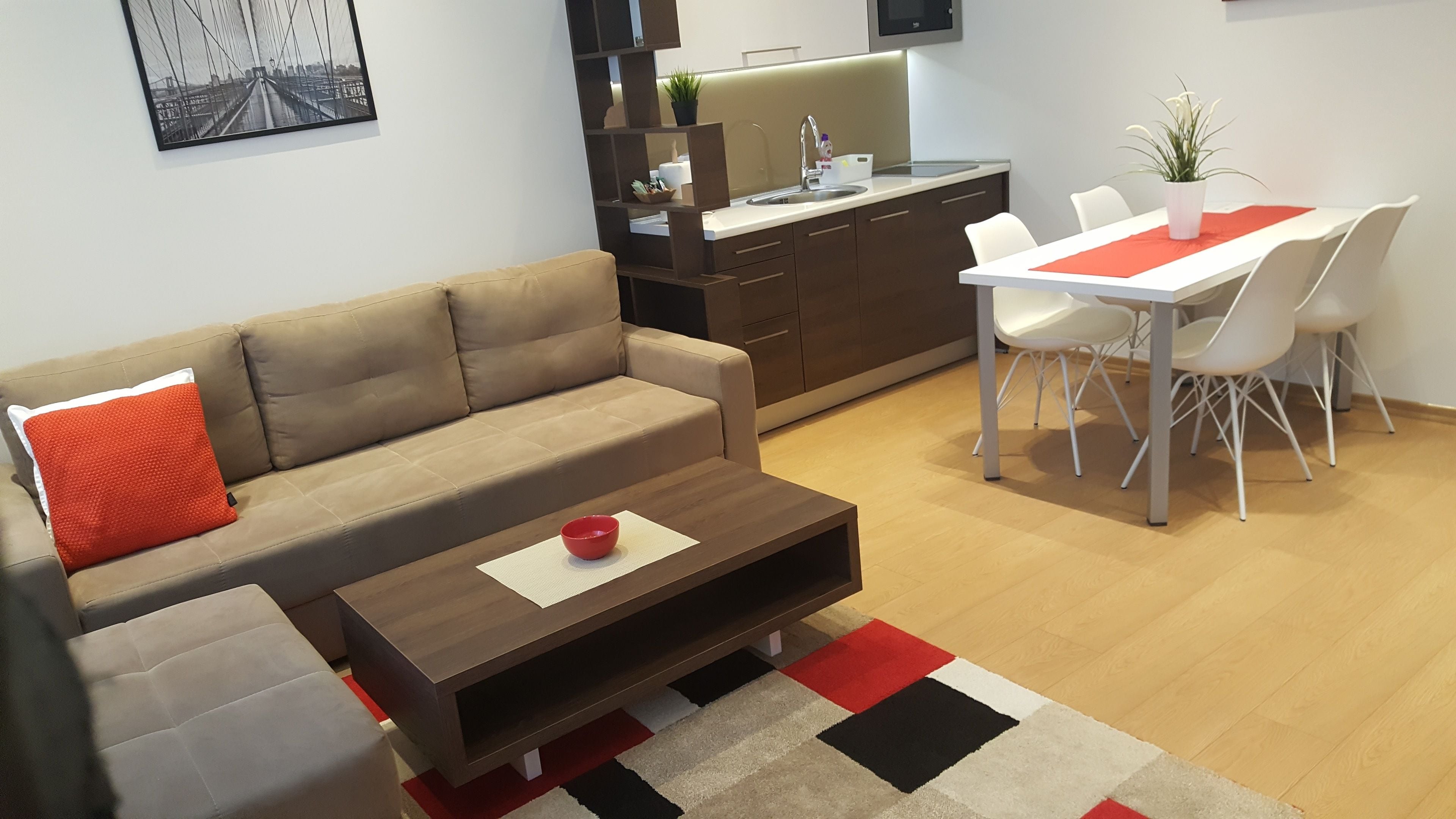 A modern living room with a sofa, coffee table, and dining area with chairs and a table.