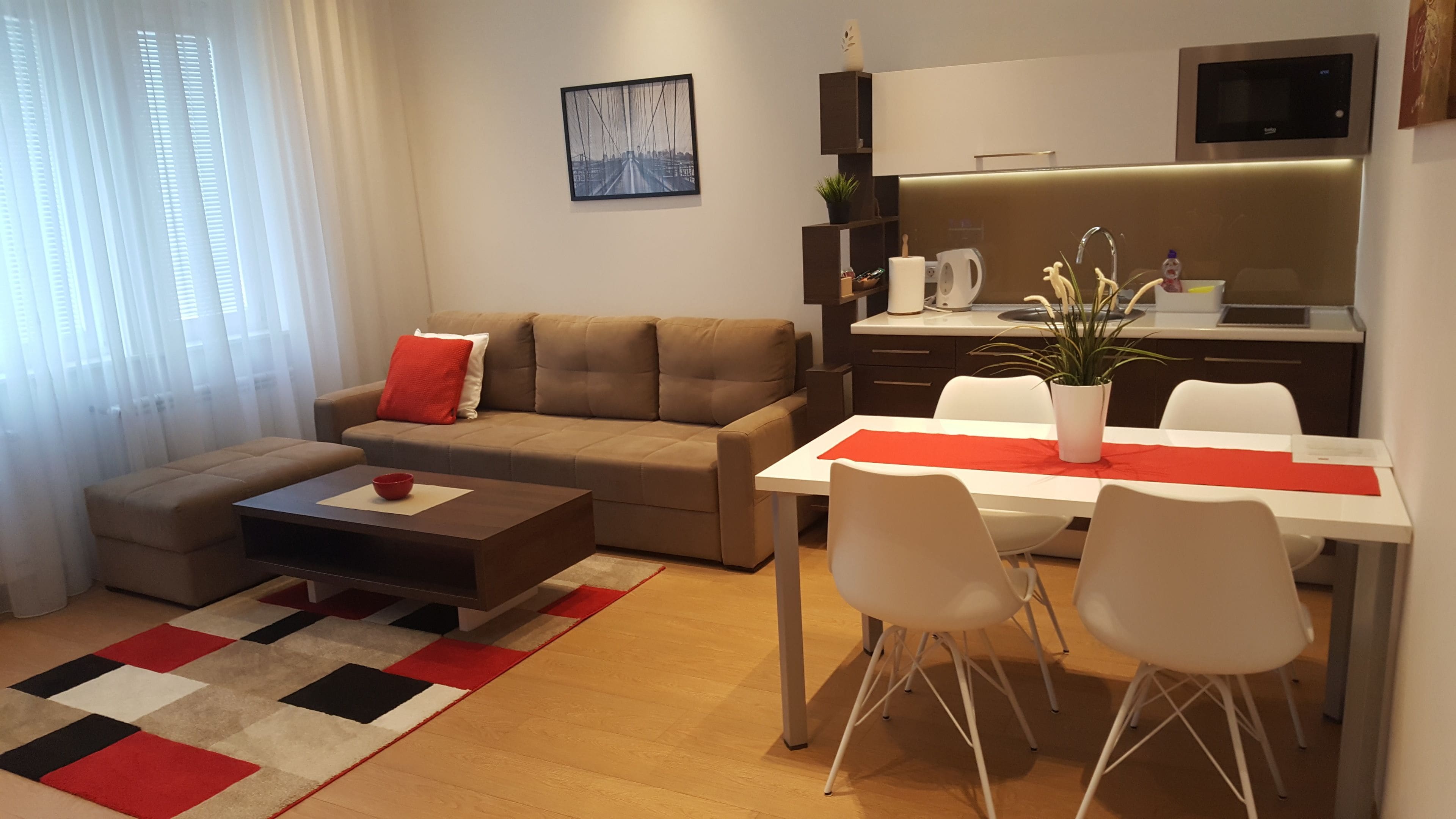 A modern living room with a sofa, coffee table, and dining area with chairs and a table.