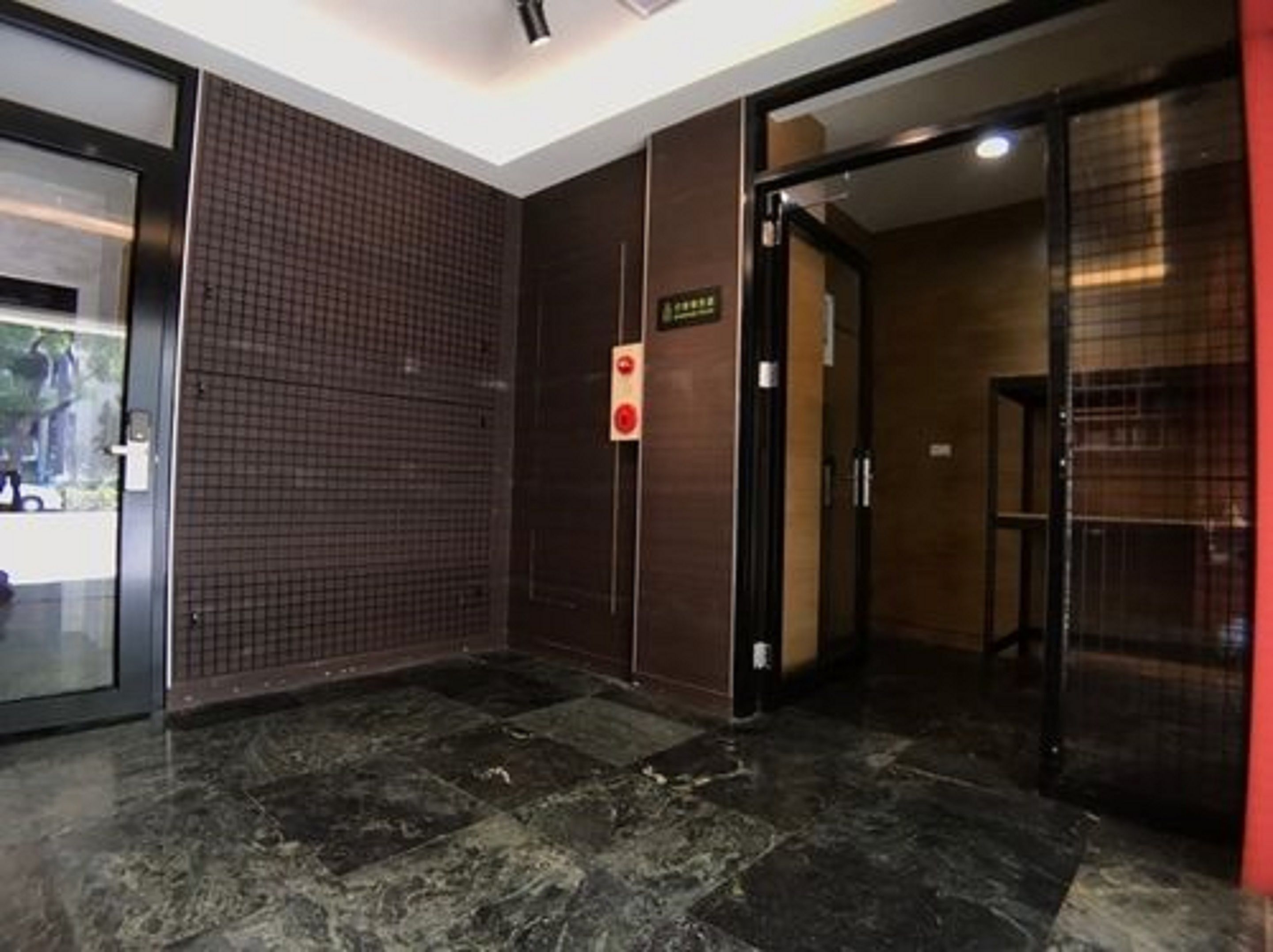A hotel lobby with a tiled wall, a marble floor, and a door leading to another room.