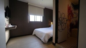 Quarto de hotel com cama, janela, pia e parede com pintura floral.