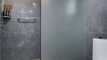 A modern bathroom with a shower, toilet, and a glass partition.