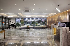 A modern lobby with a marble floor, a grand piano, a sofa, and a reception desk. - Wing Hotel Guilin - Central Square (Guilin)