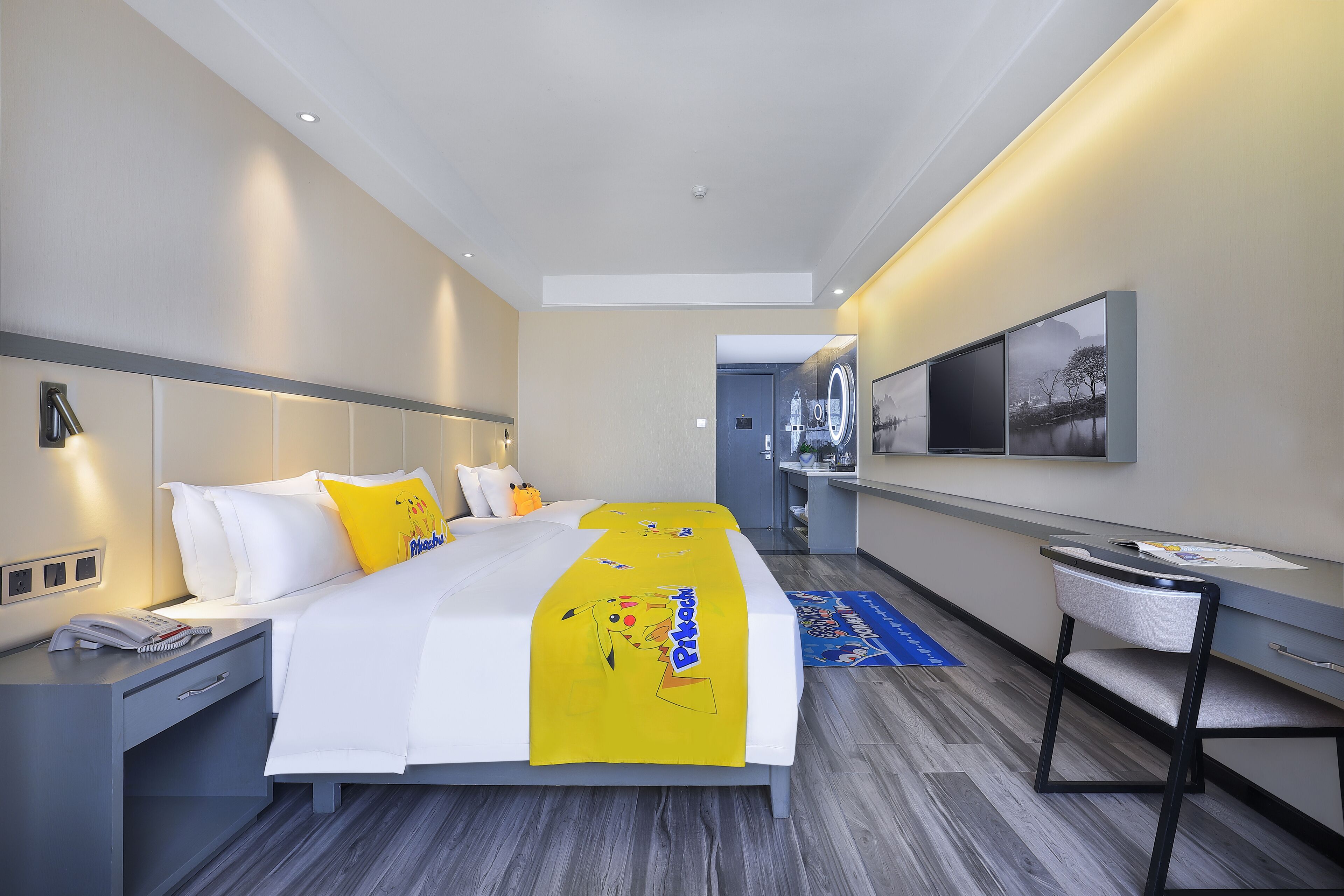 A hotel room with a bed, bedside table, nightstand, and a desk with a chair.