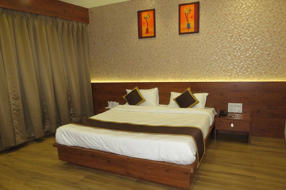 A hotel room with a large bed, wooden headboard, and a nightstand with a phone.