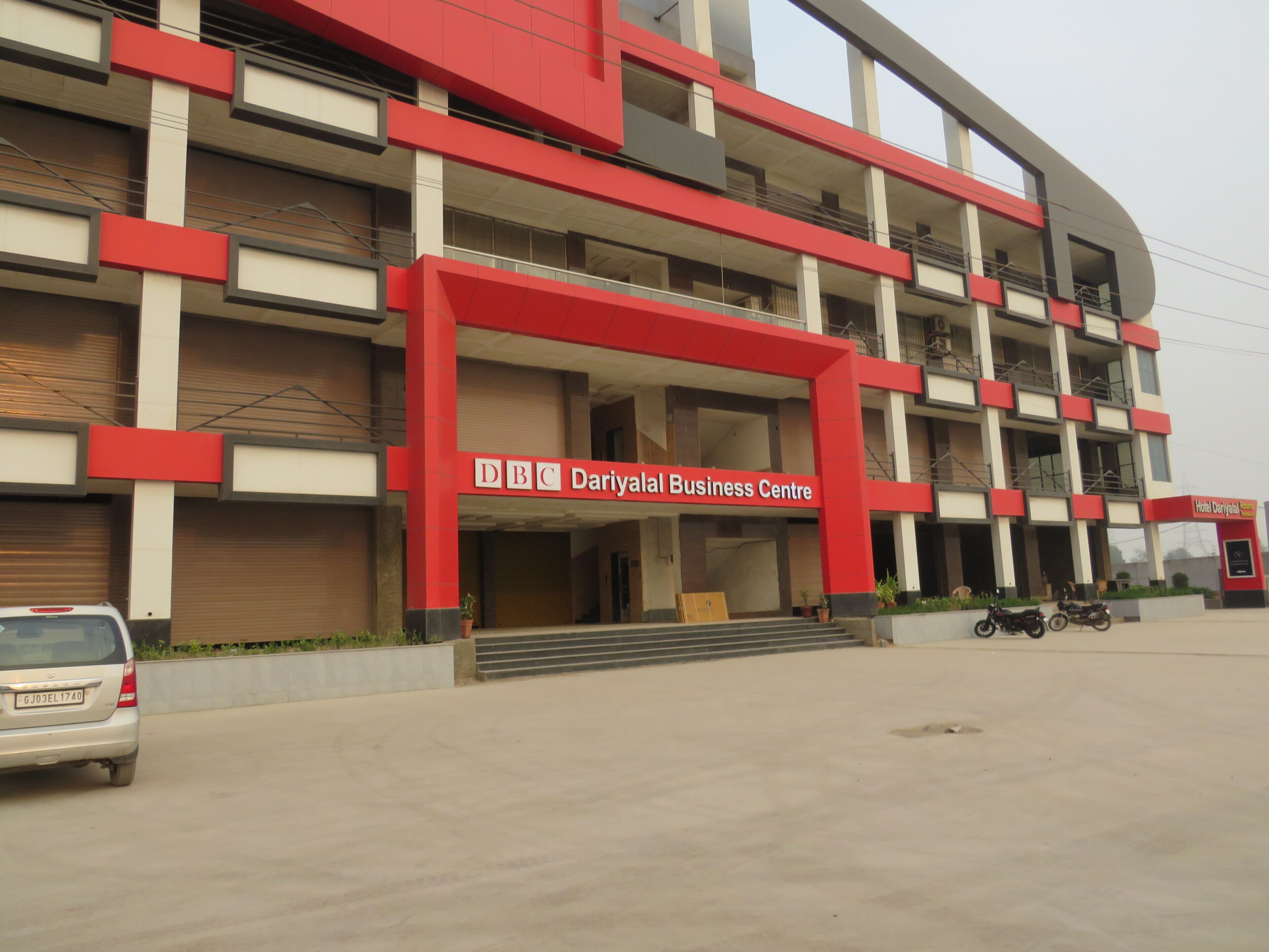 A multi-story building with a prominent red and white color scheme, featuring a sign for the DBC Dariyal Business Centre.
