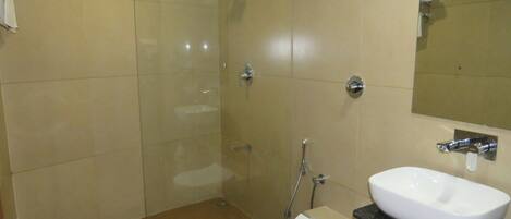 A modern bathroom with a glass-enclosed shower, a white toilet, and a large sink with a mirror above it.