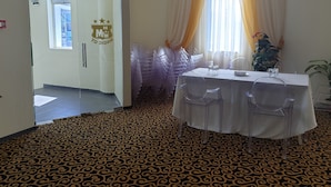 A hotel room with a patterned carpet, a table set with clear chairs, and a window with curtains. - Hotel Magic City Center (Pitesti)
