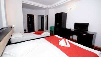 A hotel room with two beds, a desk, a TV, and a wardrobe.