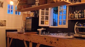 A rustic bar area with wooden shelves, a television, and various bottles. - Hôtel Escalandes (Lesperon)