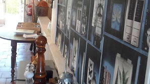 A room with a long table, shelves with various items, and a wall with framed pictures. - Hôtel Escalandes (Lesperon)