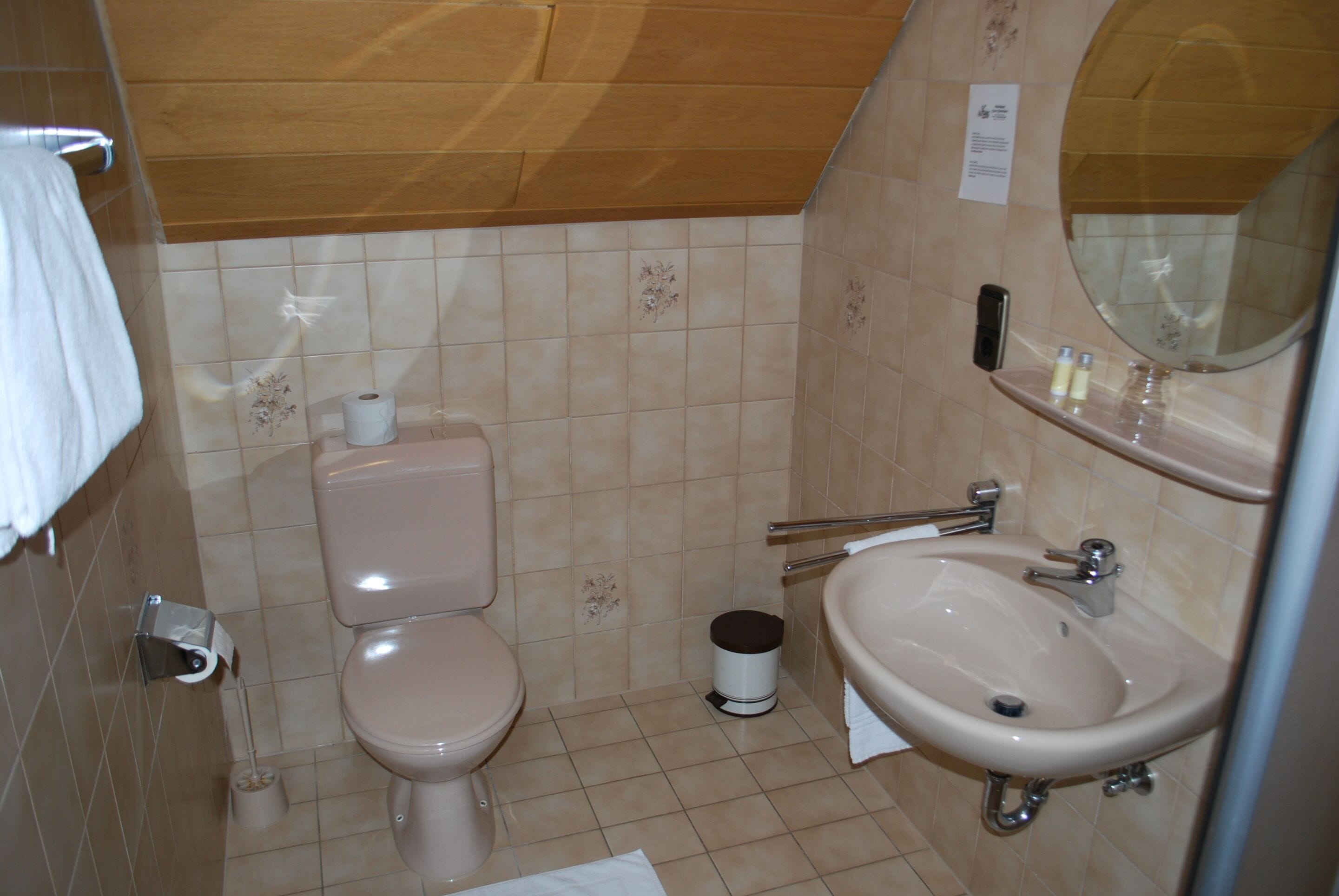 A small bathroom with a toilet, sink, and mirror.