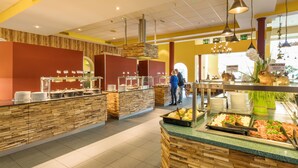 A buffet area with multiple food stations, a wooden counter, and hanging lights.