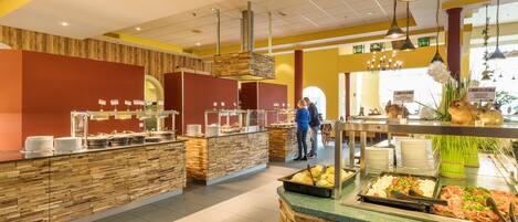 A buffet area with multiple food stations, a wooden counter, and hanging lights.