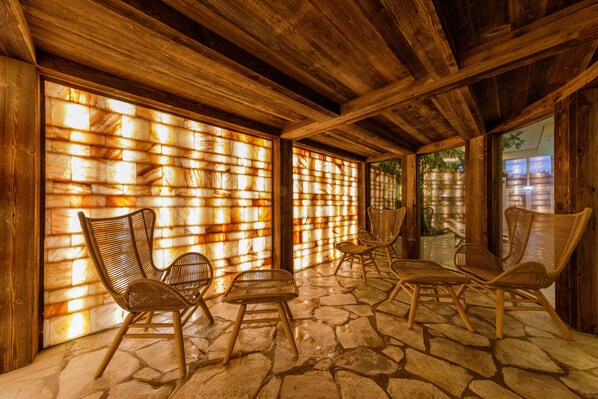 A covered outdoor seating area with stone flooring and wooden furniture. - Hotel Hochsauerland by Center Parcs (Medebach)