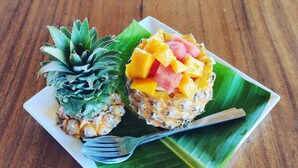 A plate with a pineapple and a fruit salad on a banana leaf. - Salt Field Glamping (Kampot)
