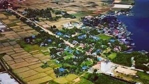 An aerial view of a coastal area with residential buildings, green spaces, and a water body. - Salt Field Glamping (Kampot)
